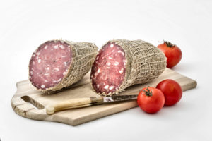 Soppressa stagionata di puro suino, prodotta in Gallura, foto su tagliere con pomodori
